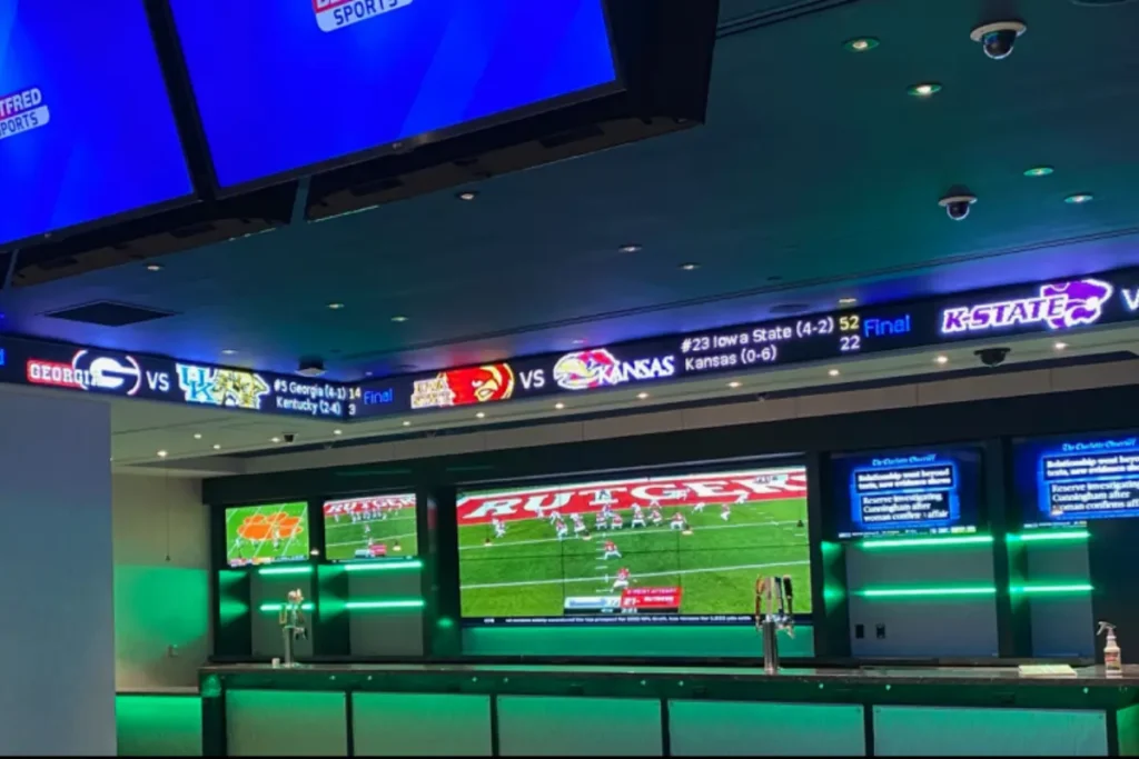 A Rise Display sports ticker installation above a sports bar serving area.